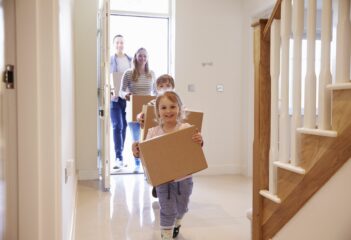 Using a solicitor estate agent when moving home. Family carrying boxes into new home on moving day.