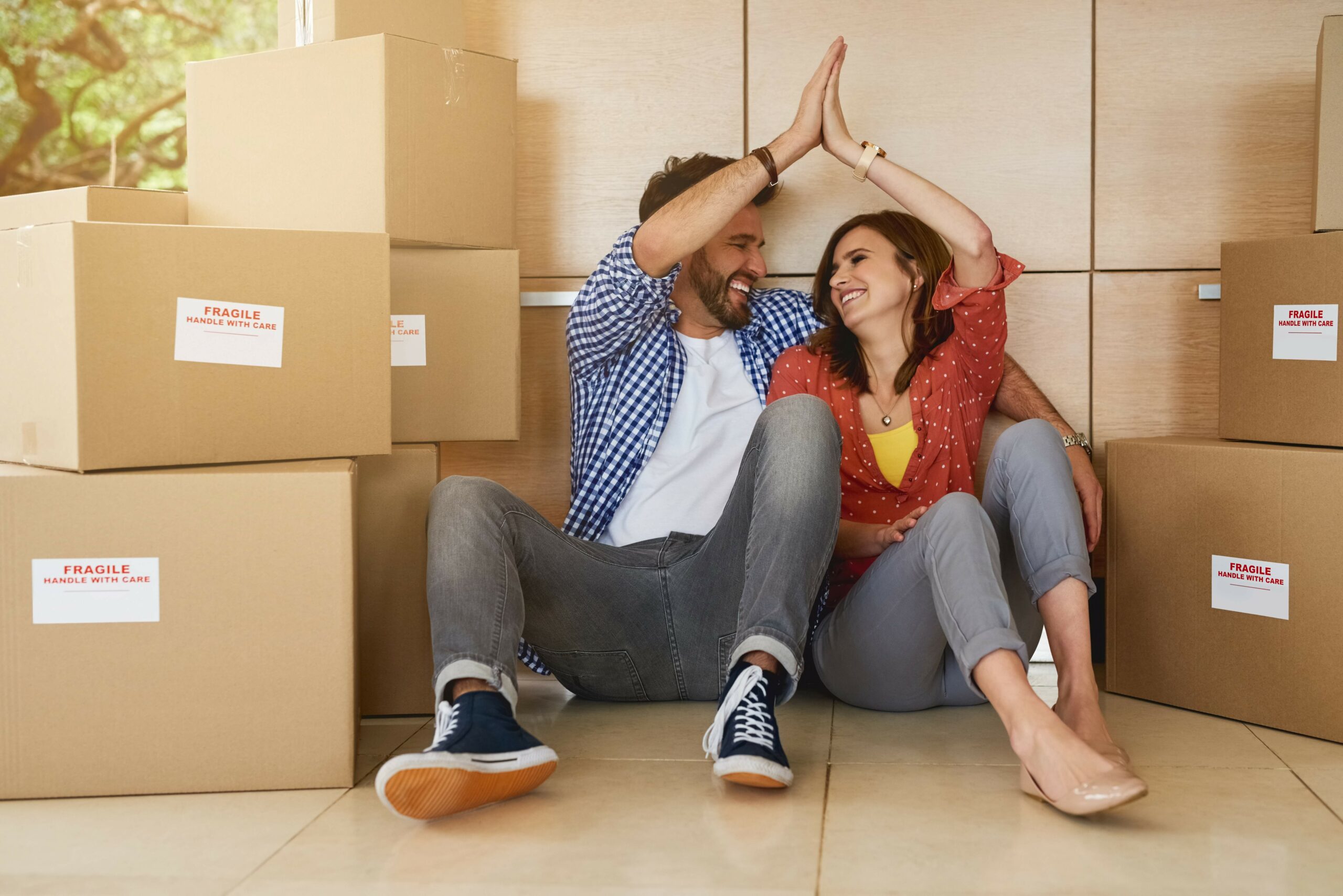 Asking price when buying a home. Shot of a young couple high fiving while moving into their new home.